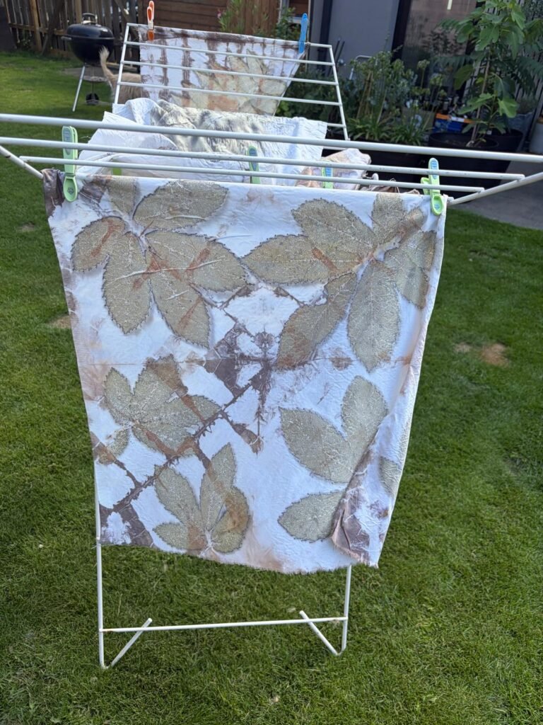 Eco-printed cloth with botanical leaf impressions hanging to dry.